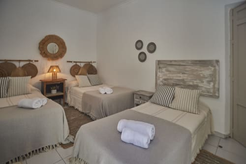 Habitación triple en Casas Cercana, Abarán: tres camas, almohadas rayadas, espejo tejido y decoración rústica
