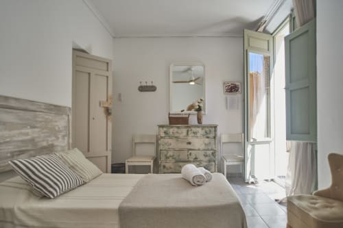 Dormitorio luminoso en Casas Cercana de Abarán con almohadas rayadas, cómoda vintage, espejo y acceso a balcón