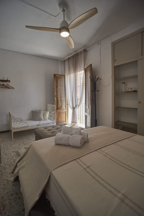 Habitación familiar luminosa en Casas Cercana con cama doble, cuna, puerta al balcón, ventilador de techo y almacenamiento integrado