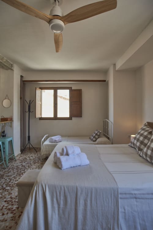 Dormitorio luminoso en Casas Cercana, Abarán, con dos camas, ventilador de madera, vistas a tejadillos del pueblo y estilo rústico