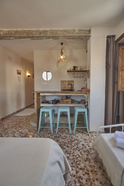 Luminoso loft en Casas Cercana con taburetes menta, cocina compacta, vigas vistas y piso rústico de terrazzo