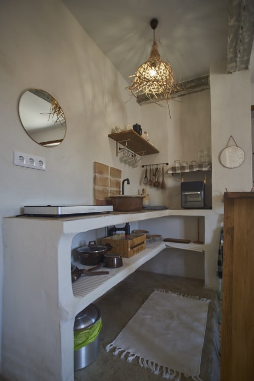 Cocina minimalista en loft de Casas Cercana con encimeras blancas, estantes de madera, iluminación colgante y decoración rústica en Abarán.