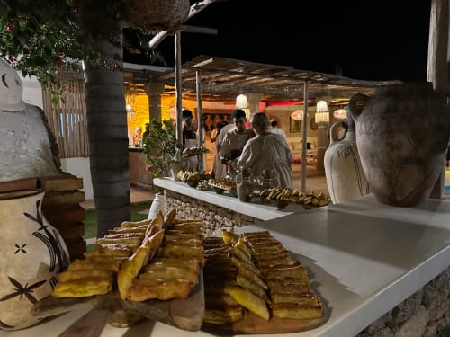 Plantains grillées présentées au marché nocturne du Riad Eucalyptus à El Ghazouane, Maroc, avec des clients dînant en arrière-plan