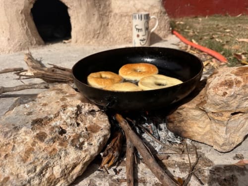 Cuisine en plein air au Riad Eucalyptus à El Ghazouane : beignets qui frient dans une poêle noire sur un feu ouvert