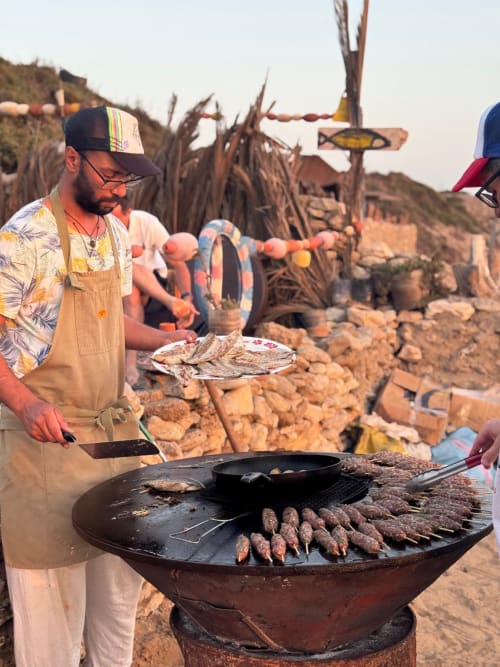 Homme faisant griller du poisson frais au Riad Eucalyptus, hôtel ethnique à El Ghazouane, Maroc