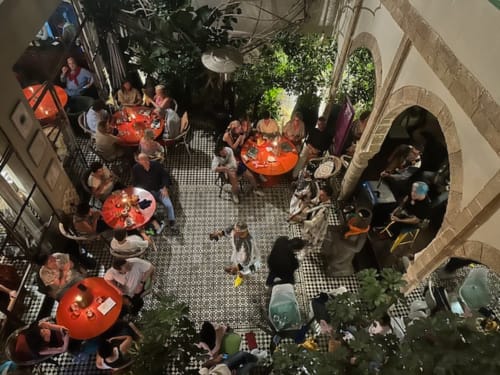 Vue aérienne de la cour du Riad Eucalyptus avec des clients dînant aux tables rouges à El Ghazouane, Maroc