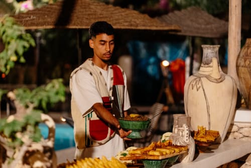 Personnel servant le repas au Riad Eucalyptus, hôtel ethnique à El Ghazouane, Maroc, service du soir avec décoration traditionnelle