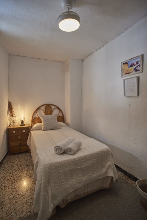 Acogedora habitación individual en Casas Cercana en Abarán con cama de madera, ropa blanca, toallas enrolladas, mesita de noche y luz de techo