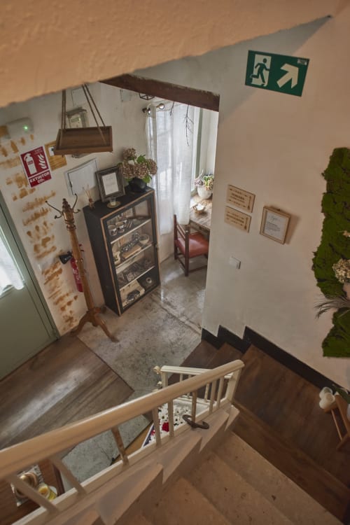 Vista de la escalera de la cabaña Casa Cercana en Abarán con vitrina, plantas y señal de salida