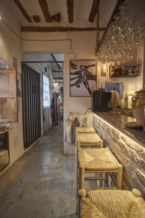 Cocina rústica con vigas de madera, sillas de enea, encimera de piedra y ladrillo visto en Casa Cercana, Abarán