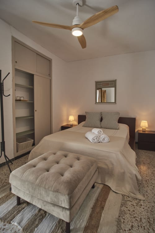 Habitación moderna en Casas Cercana de Abarán con cama matrimonial, almohadas rayadas, ventilador de techo, lámparas de noche y estanterías empotradas