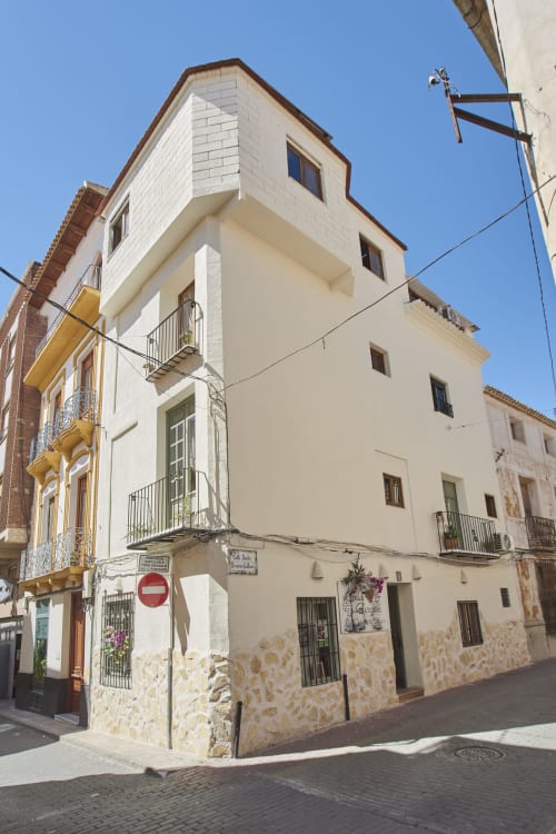 Encantadora casa de pueblo en Abarán con fachada color crema y piedra, múltiples ventanas, balcones de hierro forjado y vistas de la ciudad