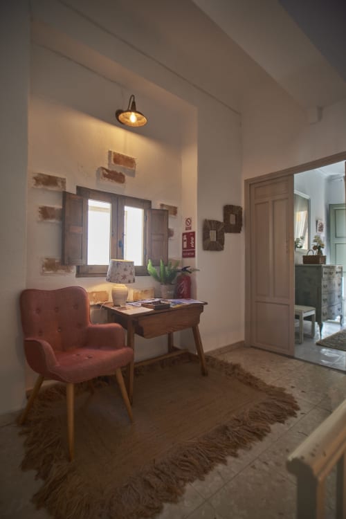 Acogedora sala de estar en Casa Cercana con sillón burdeos, escritorio de madera, ventana y lámpara colgante