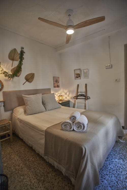 Dormitorio luminoso en la cabaña Casas Cercana de Abarán con cama, ventilador de techo de madera, plantas decorativas y toallas blancas enrolladas