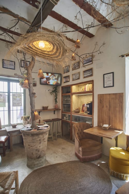 Sala de estar rústica con vigas de madera, lámparas colgantes tejidas y decoración de ramas en Casa Cercana, Abarán