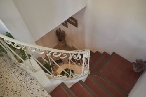 Escalera con barandillas blancas y detalles decorativos en la posada Casa Cercana de Abarán, que conduce al piso superior