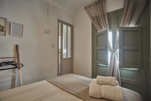 Habitación luminosa en la casita Casas Cercana de Abarán con cama, toallas enrolladas, puertas verdes con cortinas y vistas a la ciudad