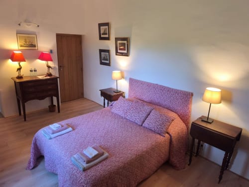 Chambre Garance at Magnanerie de Sainte Croix: elegant bedroom with pink upholstered bed, wooden furniture, warm lighting,