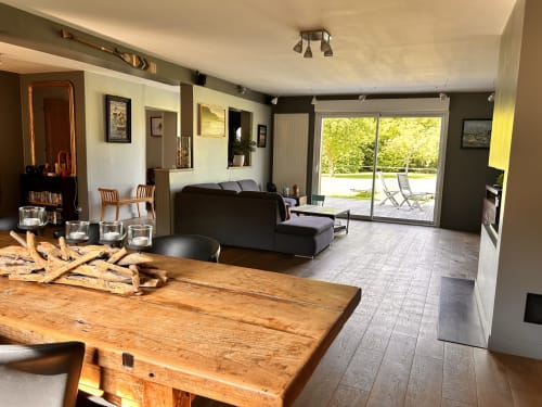 Séjour ouvert avec table en bois, canapé noir et portes vitrées donnant sur la terrasse à Mon Week End À La Mer