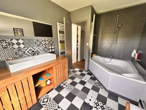Salle de bain moderne du gîte Les Sources à Mon Week End A La Mer, avec carrelage à motifs, meuble vasque en bois et baignoire d'angle