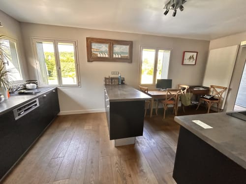 Cuisine ouverte et salle à manger avec mobilier sombre, parquet et vue sur le jardin à Mon Week End A La Mer
