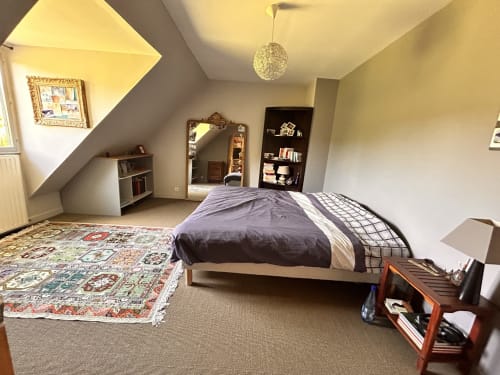 Chambre spacieuse sous les toits au cottage Mon Week End A La Mer avec lit queen, tapis décoratif, miroir, bibliothèques et lumière naturelle