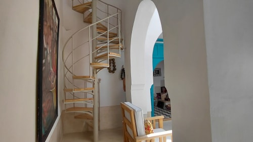 Spiral staircase and arched doorway in Riad Dar Kleta apartment in Marrakech with turquoise interior visible