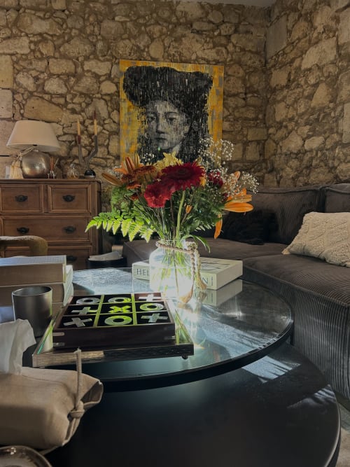 Elegant living room at La Maison du Clocher in Saint-Emilion with stone walls, modern artwork, fresh flowers, and dark