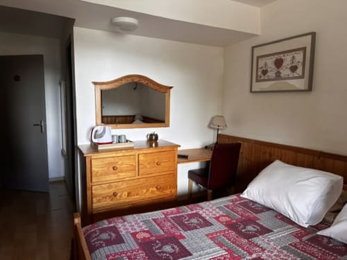 Chambre double économique à l'Hôtel la Source à La Foux avec mobilier en bois, courtepointe à motifs et espace bureau