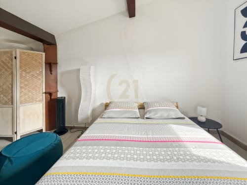 Chambre moderne d'un studio à L'Île-Rousse avec lit double, literie rayée, murs blancs et mobilier contemporain