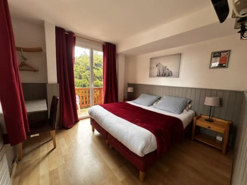 Chambre triple spacieuse et lumineuse à l'Hôtel la Source avec lits doubles, balcon, parquet et rideaux rouges