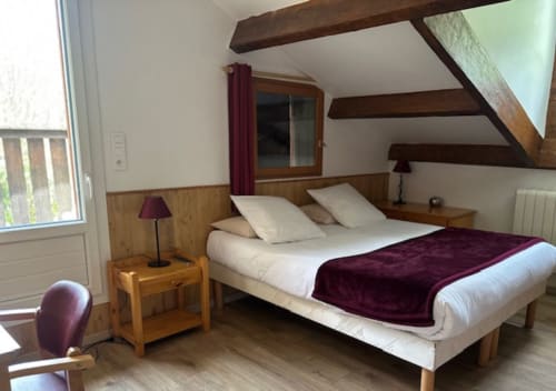 Chambre triple de l'Hôtel la Source avec poutres en bois, literie blanche, accents bourgogne et accès à la terrasse à La Foux