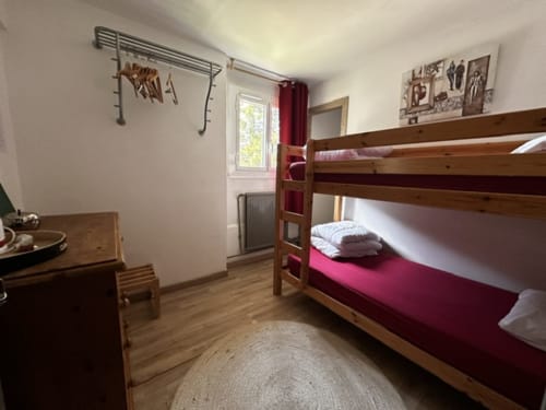 Chambre lumineuse avec lits superposés en bois et matelas bordeaux à l'Hôtel la Source à La Foux
