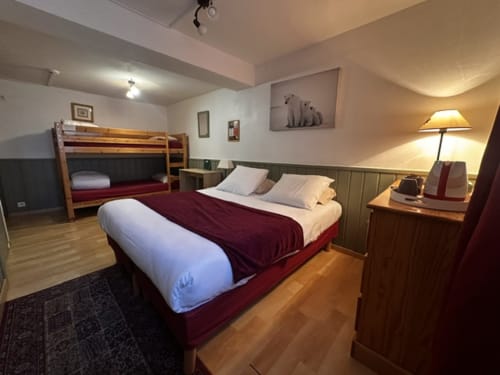 Chambre quadruple de l'Hôtel la Source avec lit double, lits superposés, mobilier en bois et éclairage chaleureux à La Foux