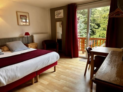 Chambre quadruple supérieure à l'Hôtel la Source à La Foux avec lit, bureau, balcon vue forêt et salle de bains privée