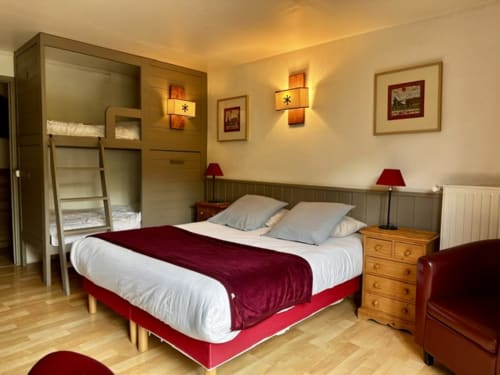 Chambre quadruple supérieure à l'Hôtel la Source avec lit queen, lits superposés et éclairage ambiant chaleureux