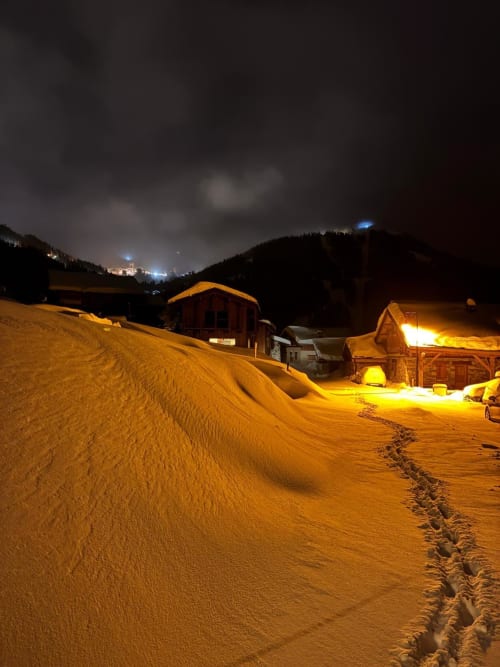 Le refuge L'Alp'In à La Plagne enneigée la nuit, chalets en bois illuminés nichés dans la vallée alpine
