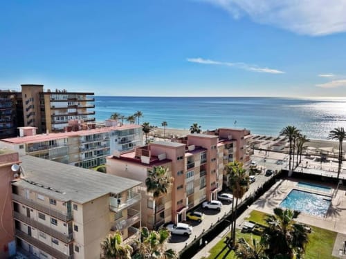 Complejo residencial frente al mar en Fuengirola con vista océano, piscina, palmeras y playa arenosa