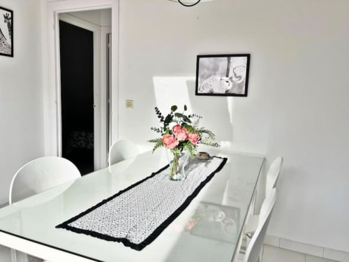 Comedor moderno en apartamento de Fuengirola con mesa blanca, flores rosas y decoración costera