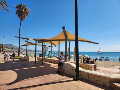 Paseo marítimo con estructuras amarillas de sombra y palmeras con vistas al Mar Mediterráneo en Fuengirola, España