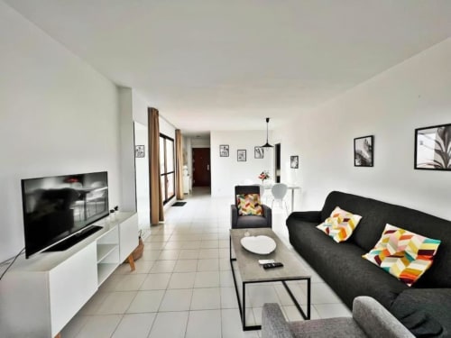 Sala de estar de apartamento de 2 dormitorios en Fuengirola con sofá negro, TV de pantalla plana, comedor y vistas al océano