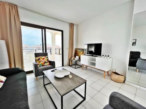 Apartamento moderno de 2 dormitorios en Fuengirola con vistas al mar, sala con sofá, TV y balcón con vista al océano y ciudad