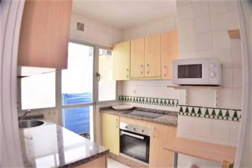 Cocina moderna en apartamento de 2 dormitorios en Fuengirola con vistas al mar, equipada con horno, microondas y acceso a balcón con vista al océano