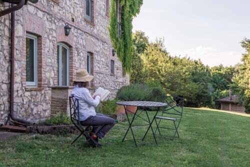 Ospite che legge a Donkeys and Roses a Viterbo, nel cortile dell'appartamento Il Casale con muri in pietra e vegetazione