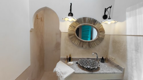 Moroccan bathroom with straw-framed mirror, patterned sink, arched doorway at Riad Dar Kleta, Marrakech