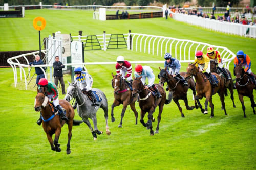 Horse race at Perth racecourse with jockeys in colorful silks racing on manicured green turf