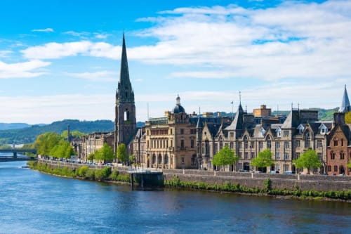 Historic riverfront buildings along the River Tay in Perth, Scotland with Gothic architecture and blue sky