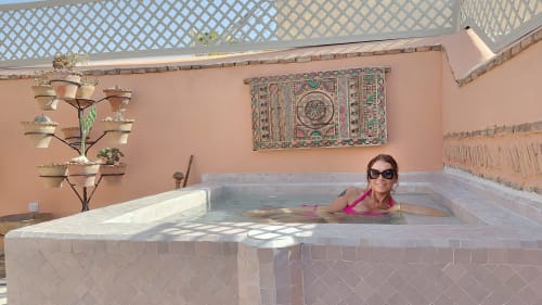 Woman relaxing in plunge pool at Riad Dar Kleta, Marrakech. Moroccan décor with tiled walls and courtyard ambiance.