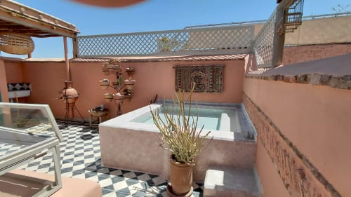 Terrace at Riad Dar Kleta in Marrakech with sunken bath, pink walls, and city views