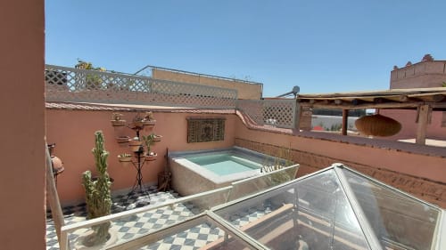 Rooftop terrace of Riad Dar Kleta in Marrakech with turquoise plunge pool, cacti, and traditional Islamic decor under blue